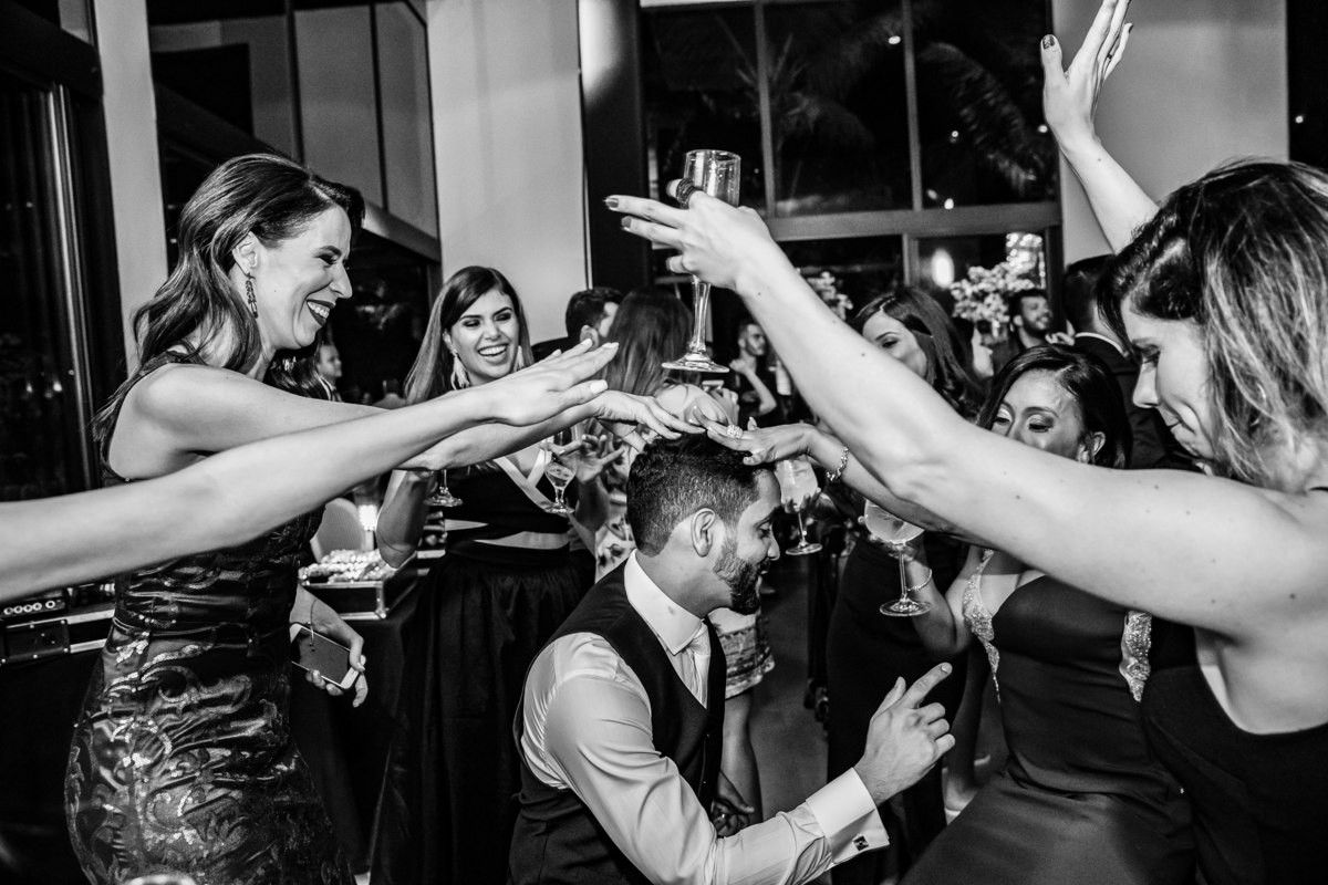 O noivo vai até o chão com as madrinhas colocando as mãos sobre ele.