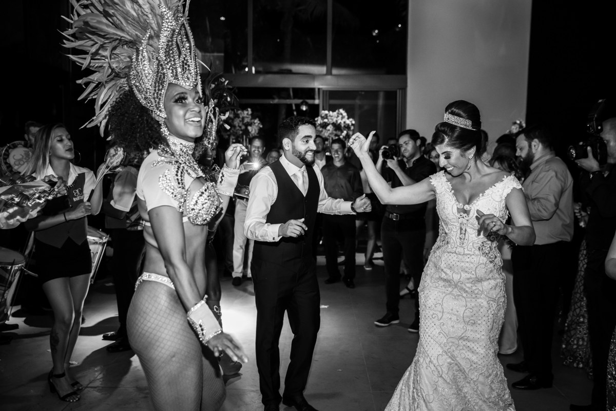 Os noivos com o samba no pé ao lado da passista da escola de samba.