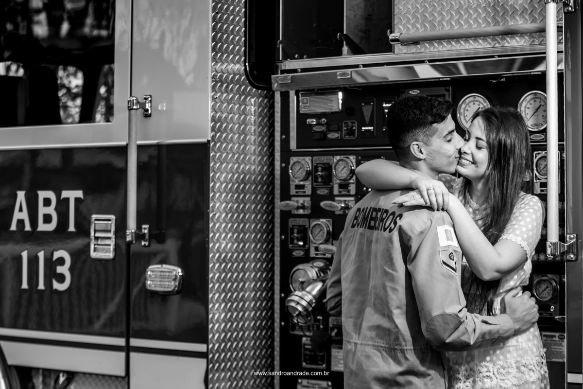 Agora na lateral do caminhão, onde tem os painéis de comando o noivo carinhosamente beija no canto da boca de sua amada Hamanda, uma fotografia preto e branca.