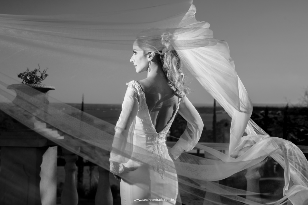 Uau...simplesmente linda, como descrever esta fotografia? A noiva de costas, com todos os detalhes e o véu voando, retrato preto e branco.
