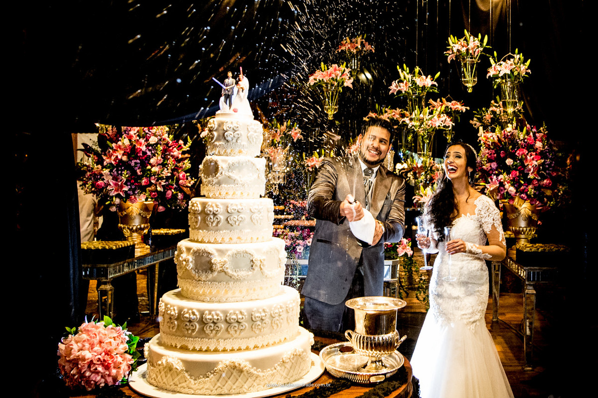 os noivos brindam próximo ao bolo