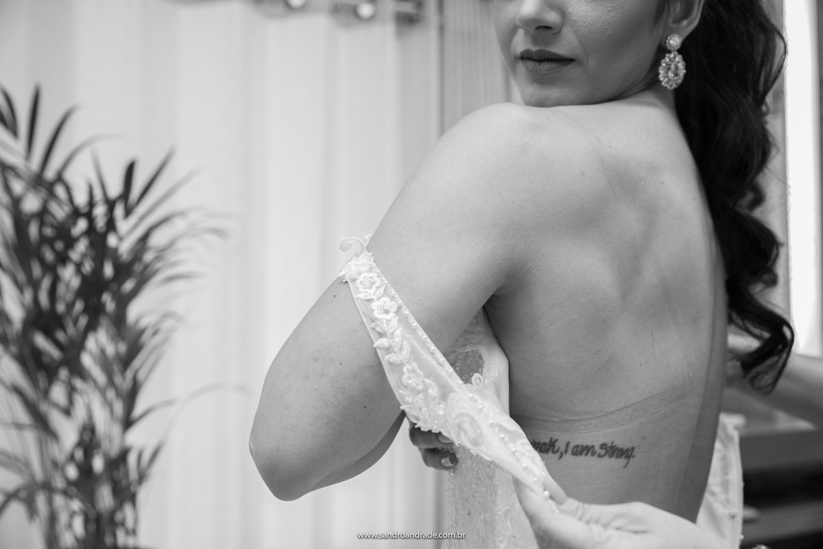 Detalhes nunca faltam em nossos trabalhos, nesta fotografia em preto e branco, vemos o detalhe da tatuagem da noiva em sua costela com o vestido ainda aberto.