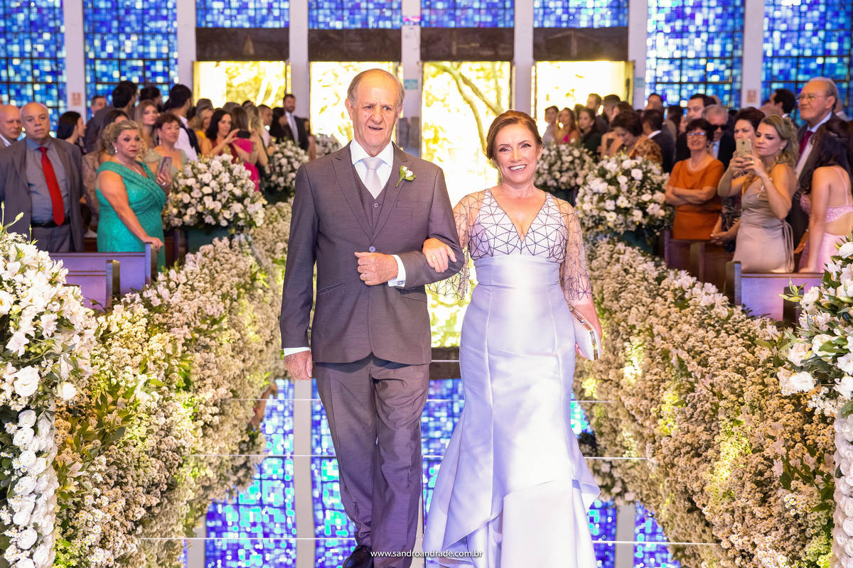 Entrada do pai do noivo com mãe da noiva, extremamente elegantes e felizes.