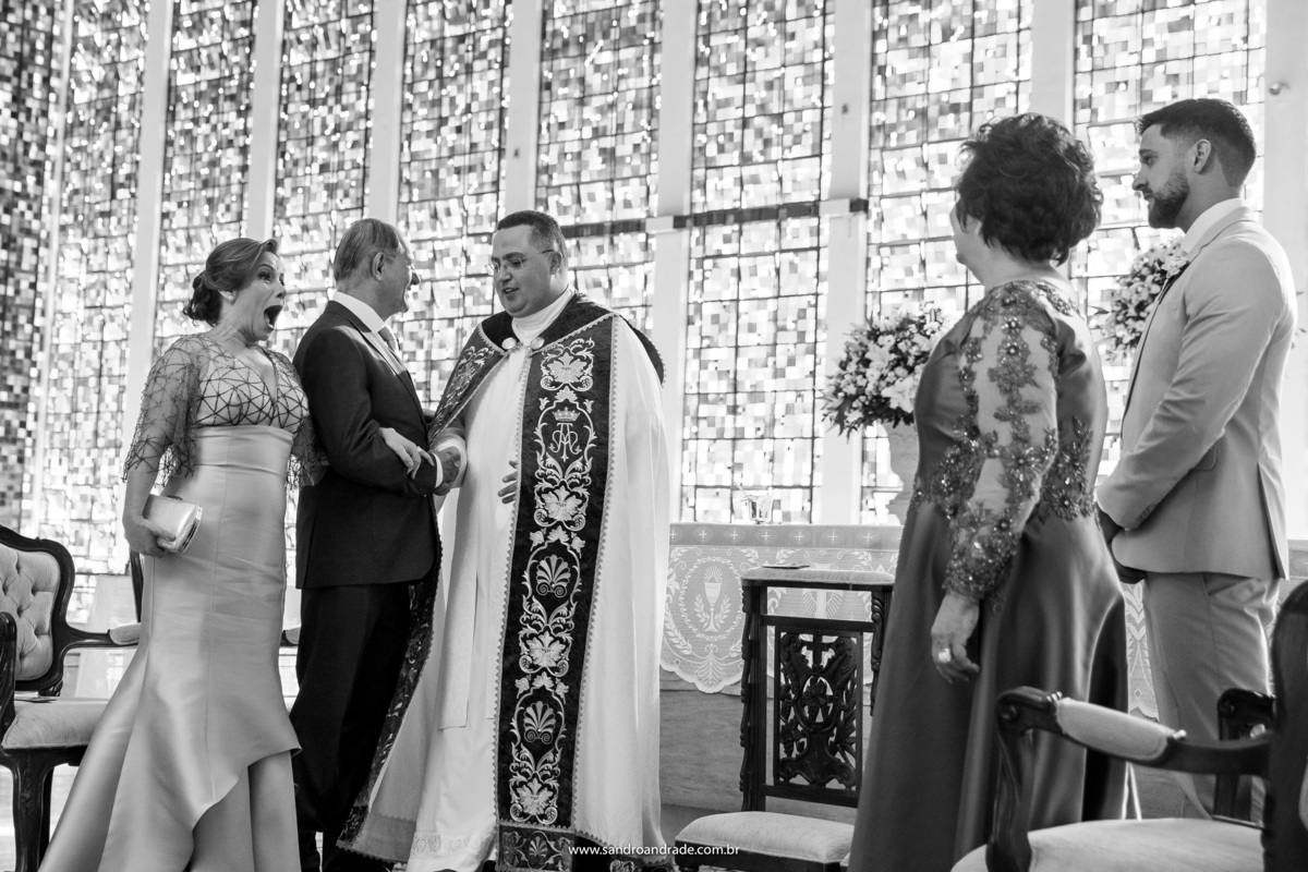O pai da noiva cumprimentando o padre, todos no altar ja a espera da noiva, que está linda.