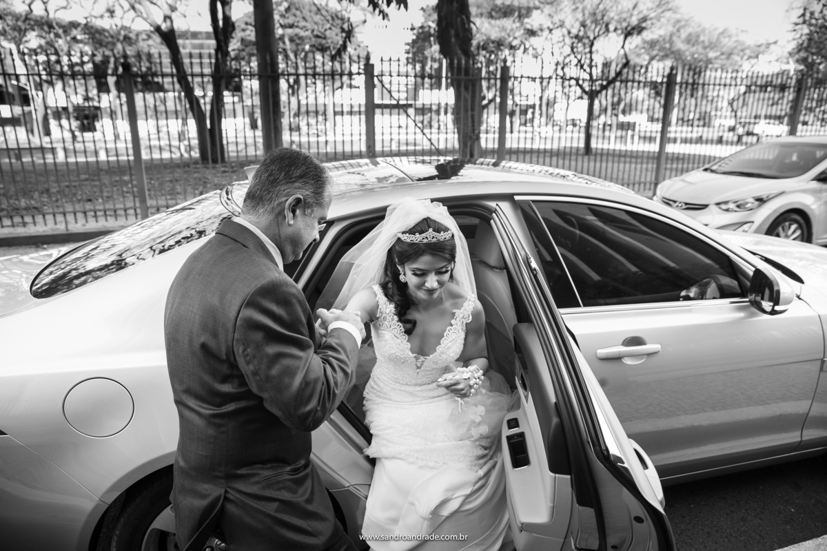 O pai da noiva, da a mão a sua filha para ela sair do carro, fotografia em preto e branco.