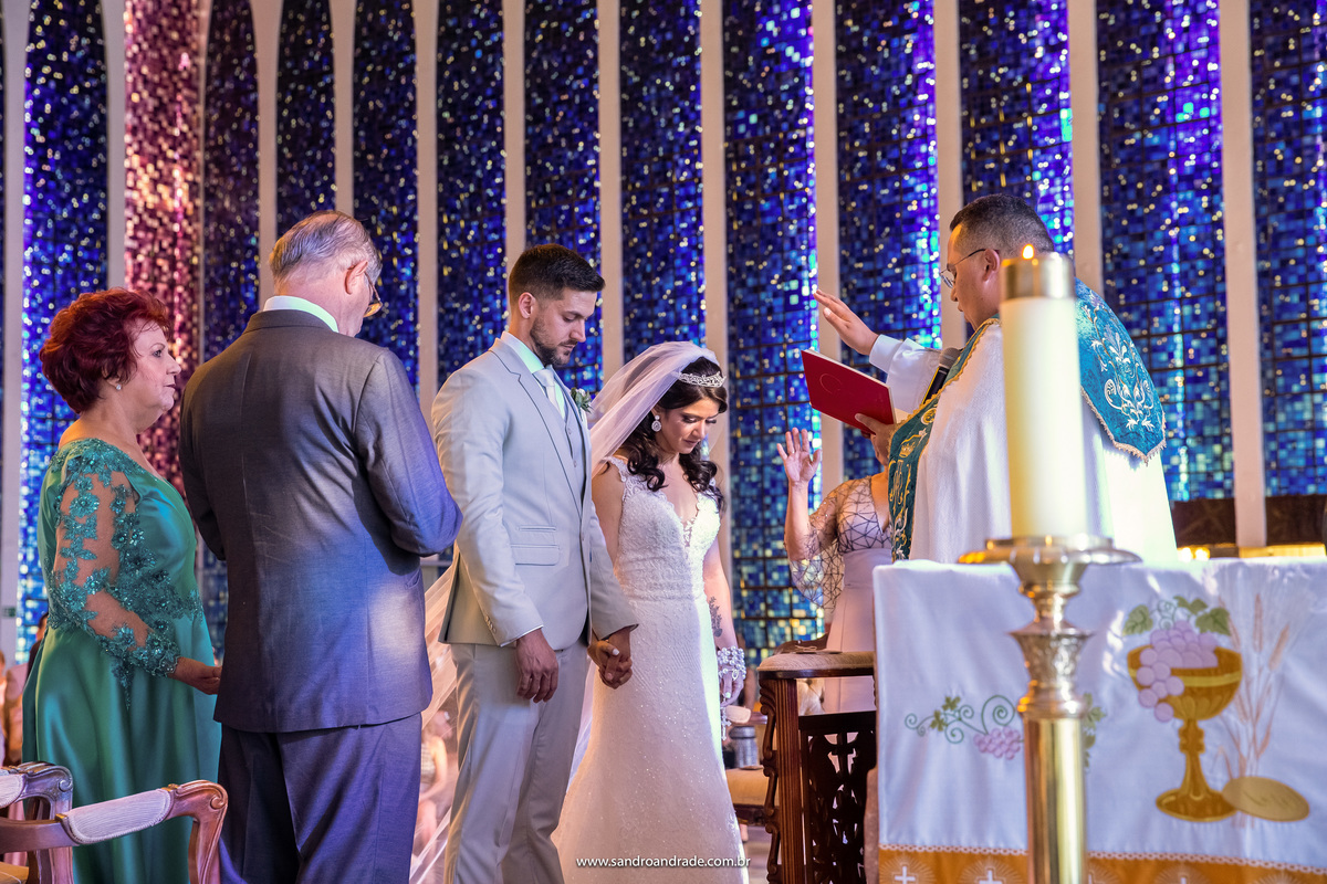 Os noivos. o padre e os pais em volta do casal dando a benção.