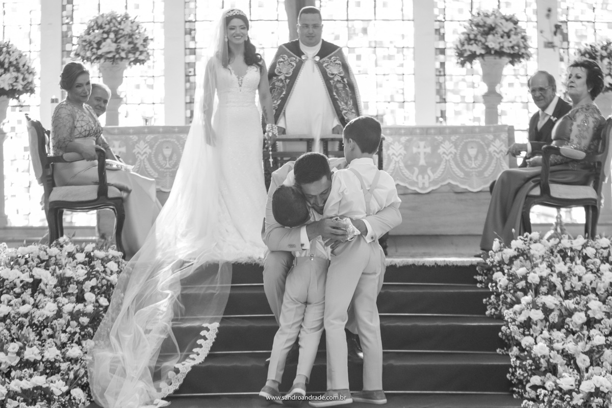 O noivo abraça os pajens que levaram as alianças até o altar, emocionante.