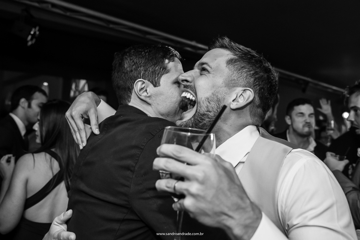 Feliz o noivo sorri com seu amigo, enquanto o abraça.