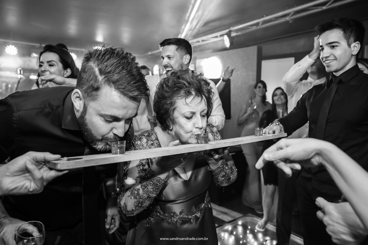 A mãe do noivo e um convidado tomando a cachaça no vira-vira...ao fundo o noivo se diverte e chama sua tia para entrar na brincadeira.