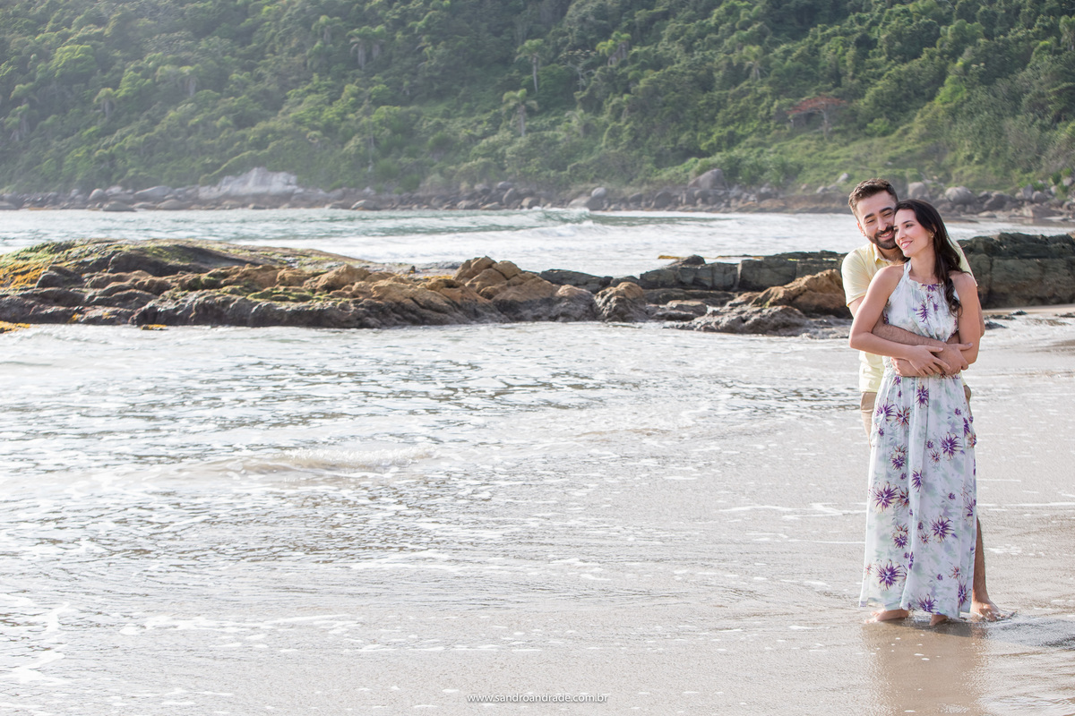 Já é dia...o grande dia e eles resolveram terminar o ensaio que começaram no dia anterior. O casal na praia de Bombinhas, muita água do mar, pedras e a vegetação.