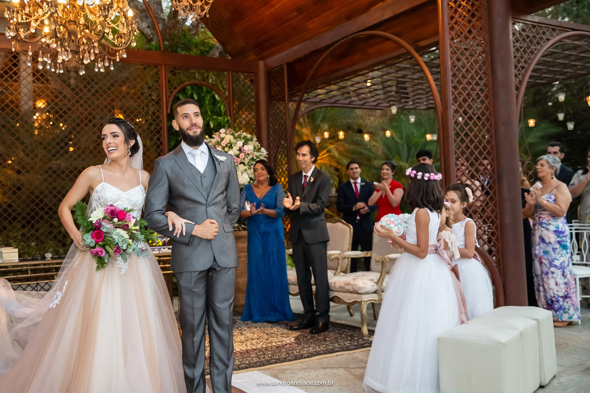 Se preparando para a saída, os convidados os aplaude, ela feliz e ele olha para o céu.