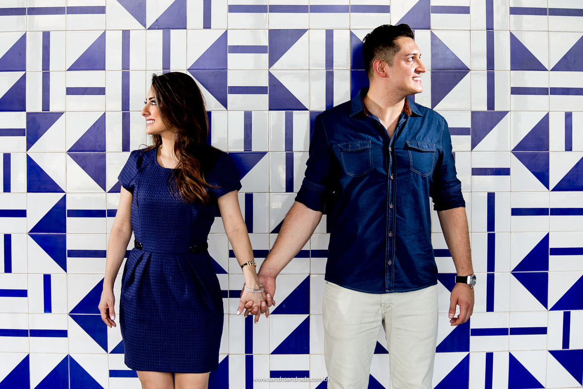 De mãos dadas o casal olha um para cada lado dentro da torre de tv com os azulejos de Athos Bulcão.