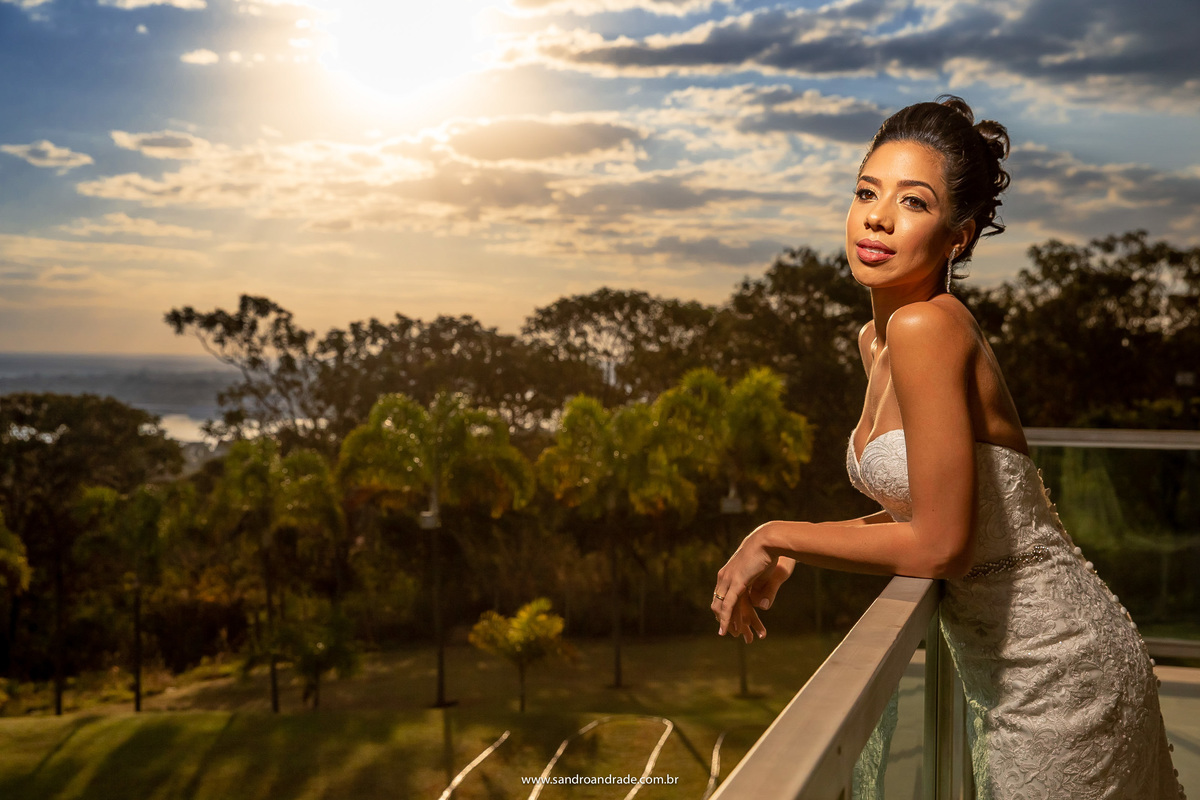 Um belo por do sol da varanda do espaço panorama, local onde aconteceu o casamento de Vanessa e Gabriel. Nesta foto a noiva esta com os braços na sacada e admira a vista do lago.