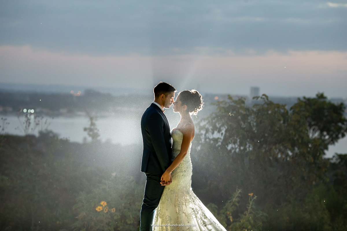 Uma fotografia diferente, com uma luz bem trabalhada no contraluz, iluminando o casal, vazando raios de luz entre eles.