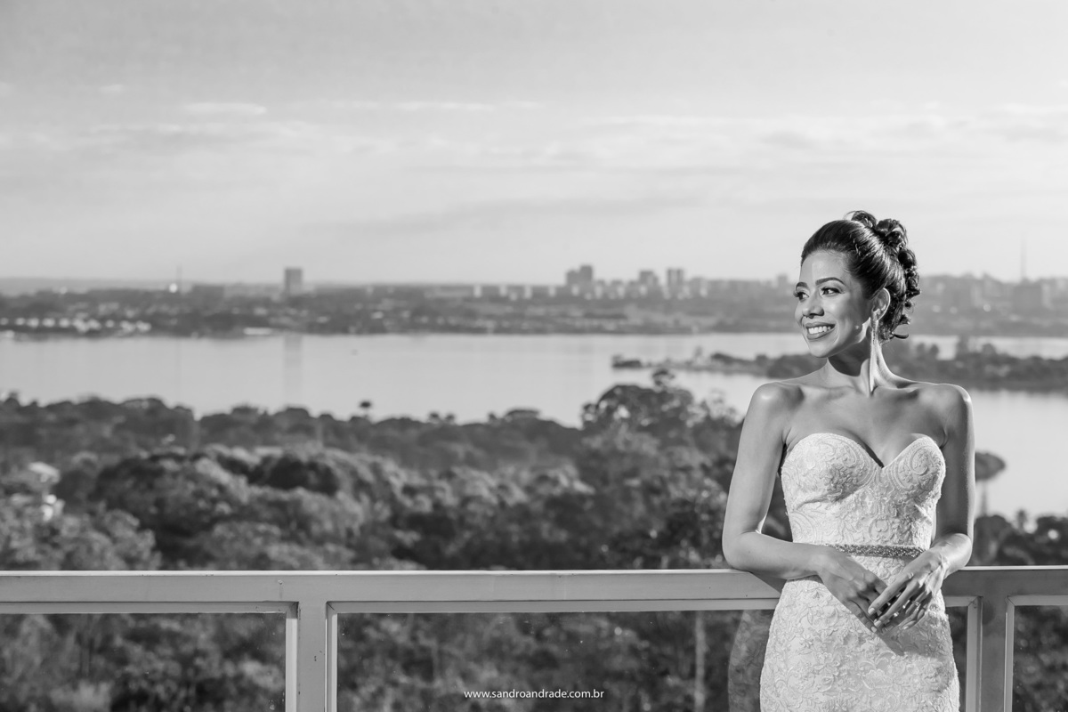 Recostada na sacada, Vanessa sorri, toda a vista do lago de fundo.