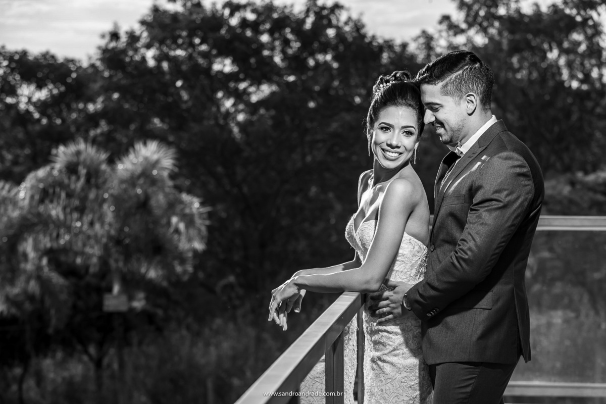 Agora os noivos, Gabriel abraça Vanessa por trás e a olha com um olhar apaixonado, enquanto ela sorri. Fotografia preto e branco feita pelo fotógrafo de casamento Sandro Andrade.