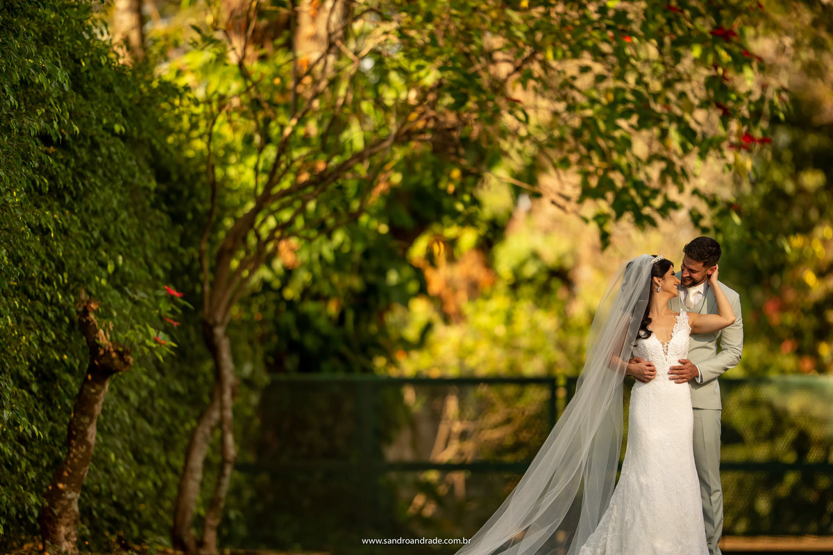 Abraçando sua agora esposa pelas costas, Michell a olha, enquanto Luiza leva mão em seu rosto e lhe da um carinho.