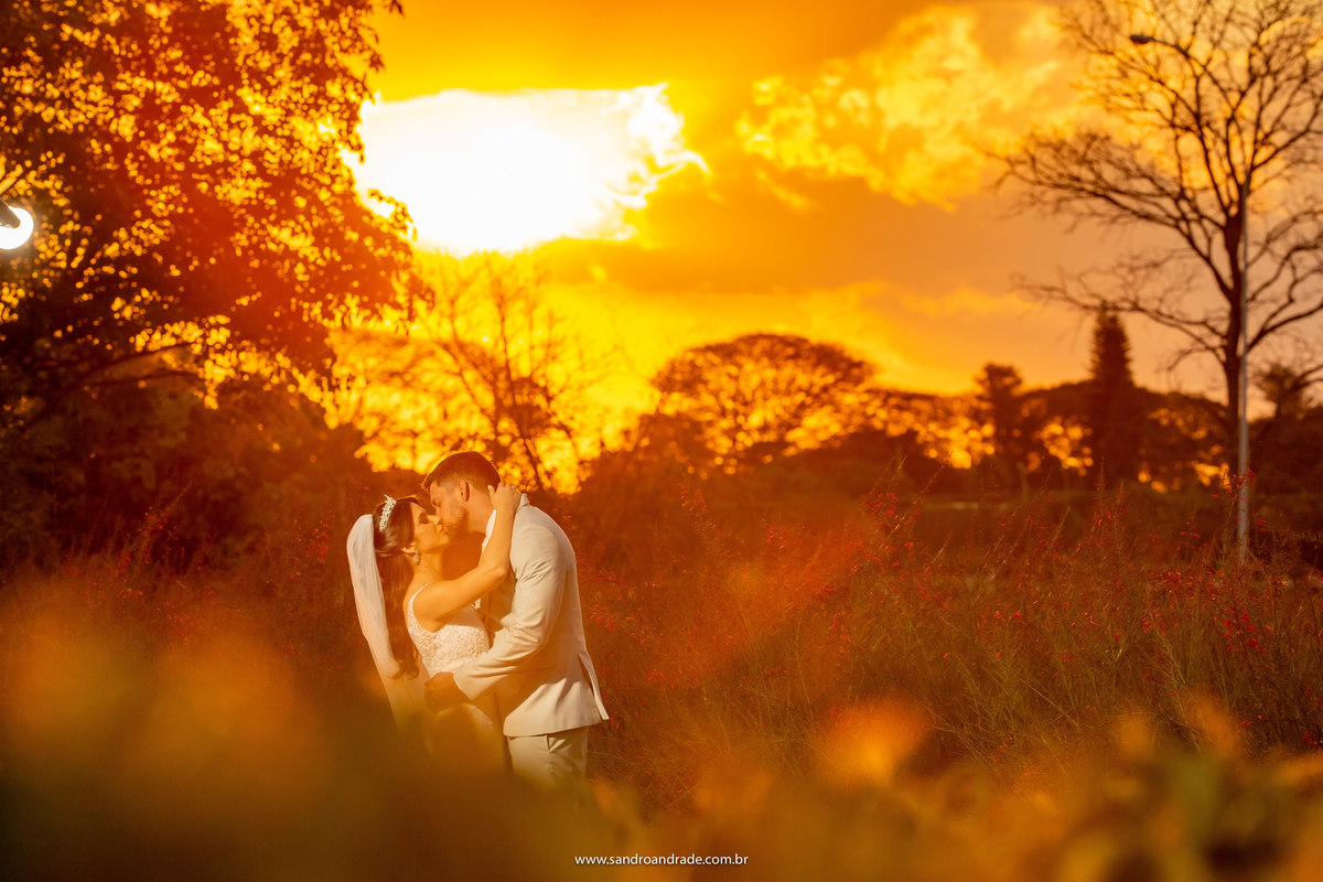 Com um beijo apaixonado, Sandro Andrade continua aproveitando o belo casal com este belíssimo fundo desse por do sol maravilhoso e com flores e árvores a frente e no fundo. Mais uma imagem top do nosso fotógrafo de Brasília.