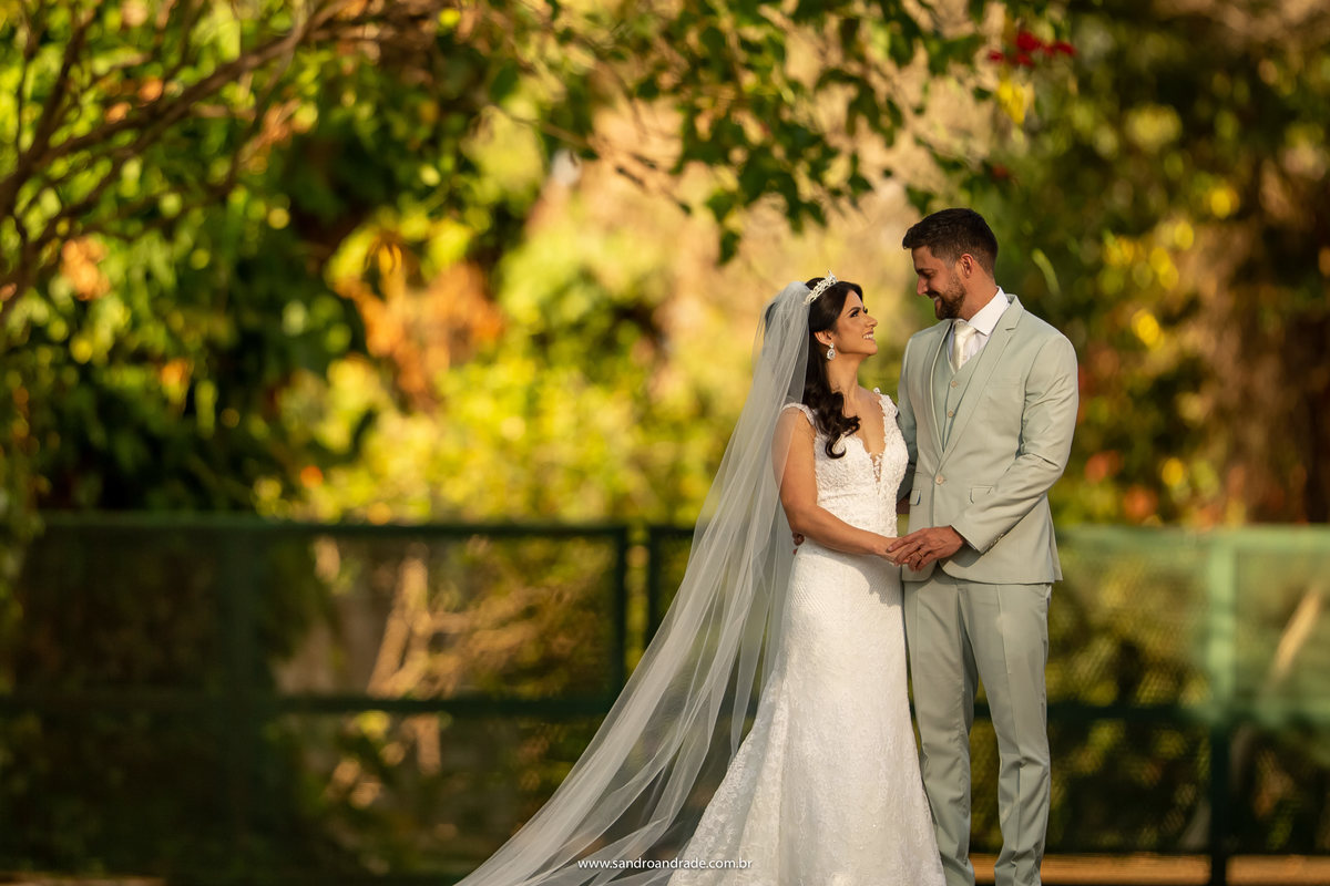 Luiza e Michell se olham apaixonados pensando na lua de mel, de mãos dadas e felizes...sorriem.