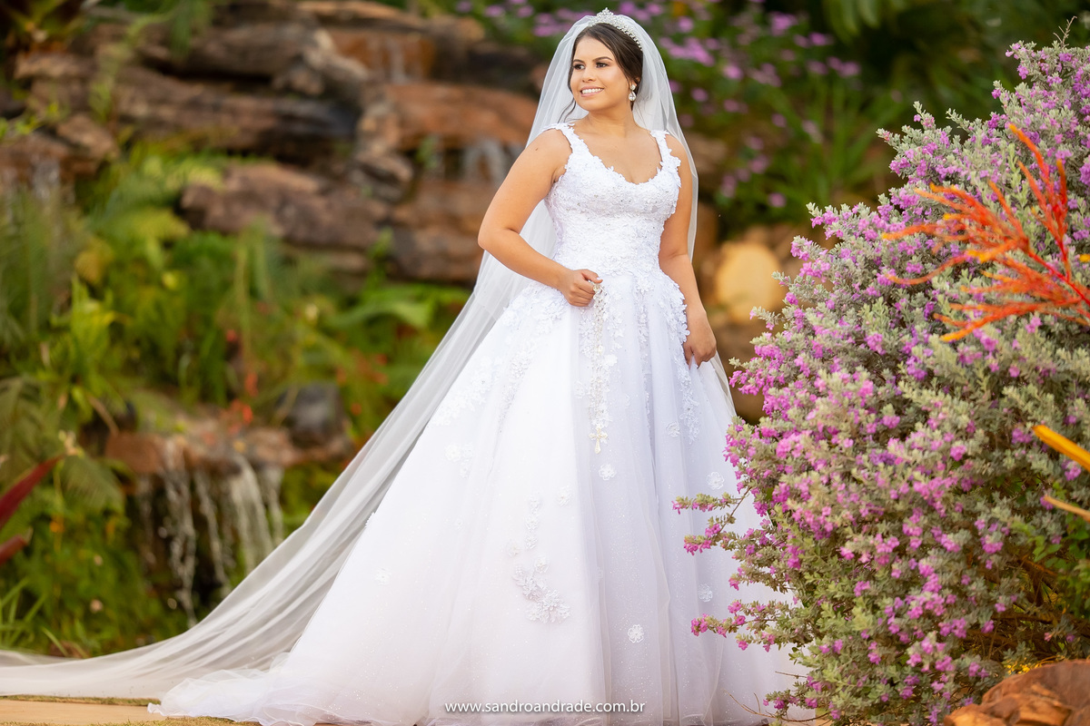 Uma fotografia da noiva de corpo inteiro, segurando seu terço, com um lindo vestido do ateliêr Fernando Peixoto, produção por Isabel de Santis Oficial. A noiva esta  simplesmente linda.