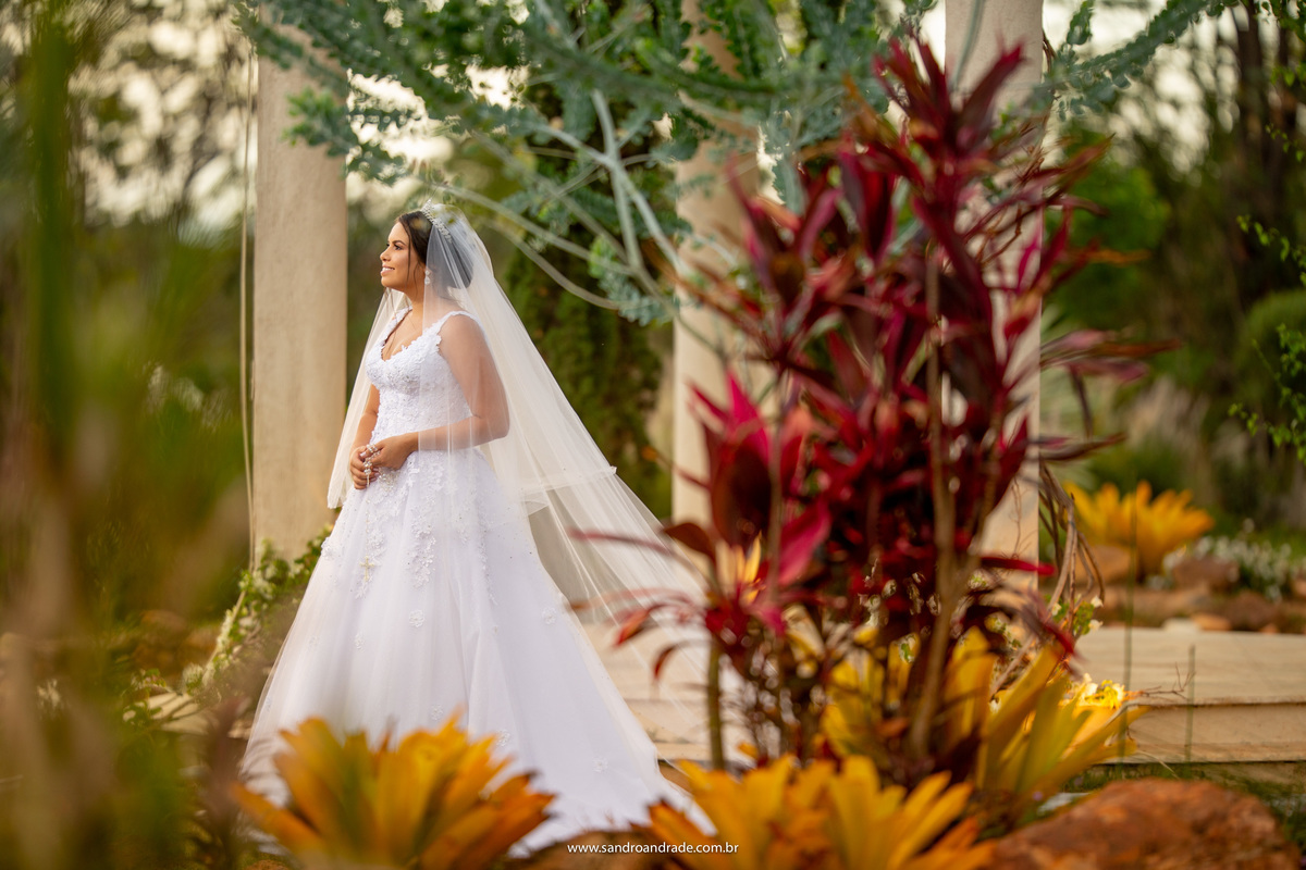 Já no gazebo, Julia olha para o palato, enquanto Sandro a fotografa por de trás das plantas e sutilmente ela está linda lá atras, Sandro é um fotógrafo premiado, um dos melhores fotógrafos do Brasil.