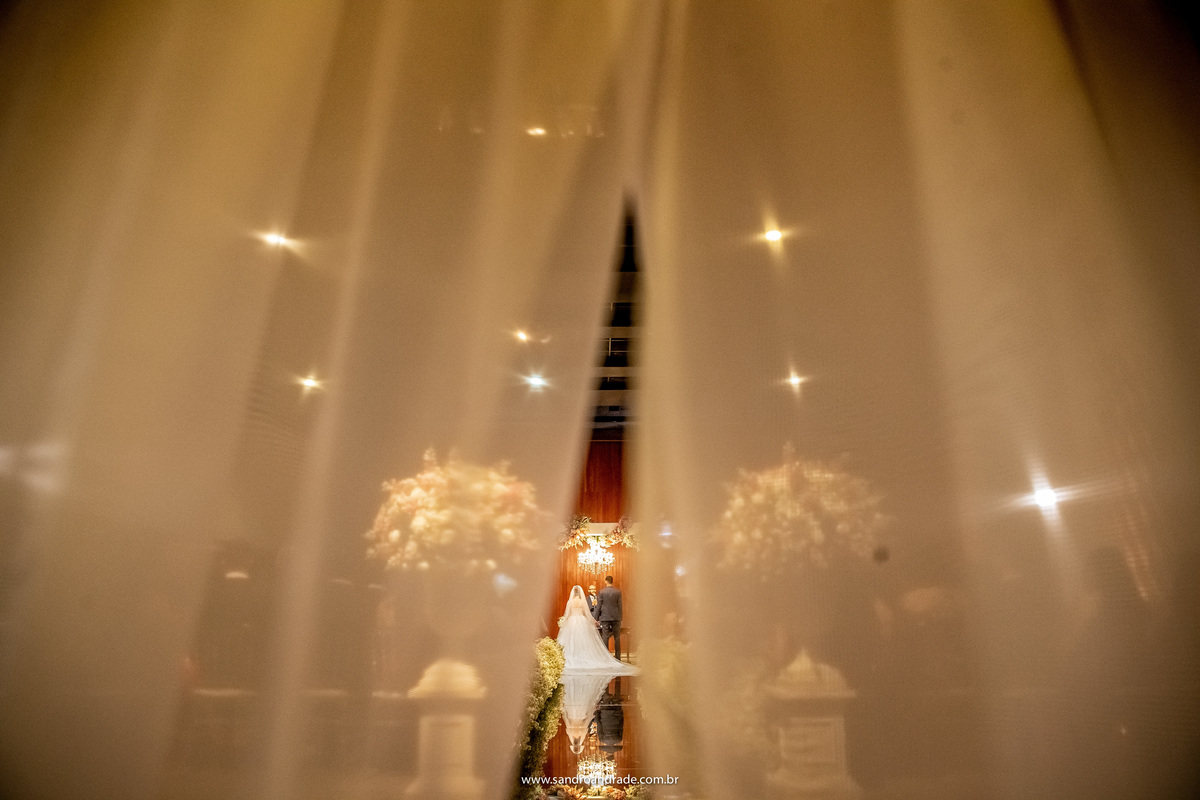 Sandro Andrade é um fotografo premiado em associações do mundo inteiro, esta imagem mostra do que ele é capaz. O casal está ao centro da fotografia, uma imagem colorida, as cortinas estão quase fechadas, fazendo uma moldura no casal, tudo em tom amarelado