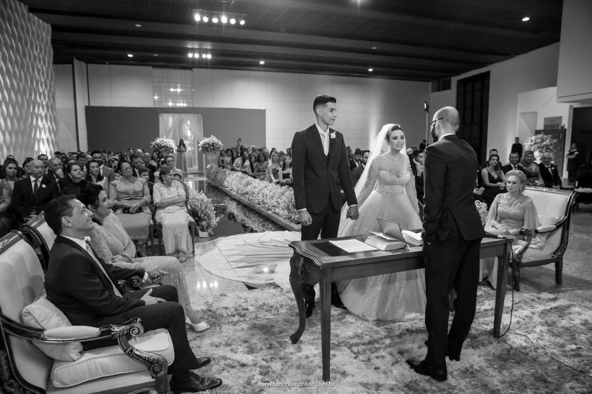 Fotografia tradicional durante a cerimonia, em preto e branco, cerimonia rolando e todos muito atentos.