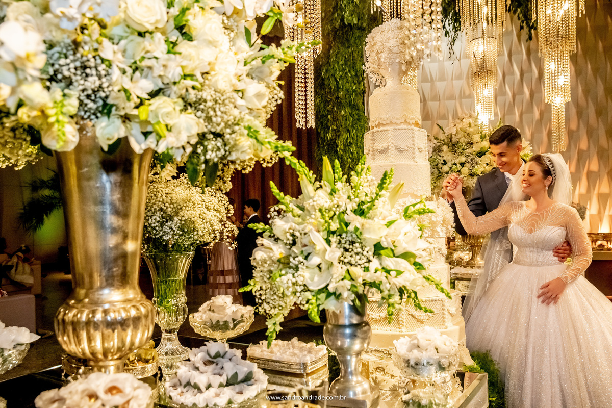 Linda decoração e um casal lindo, cortando o bolo de um jeito diferente (risos) como se estivesse com raiva do bolo.