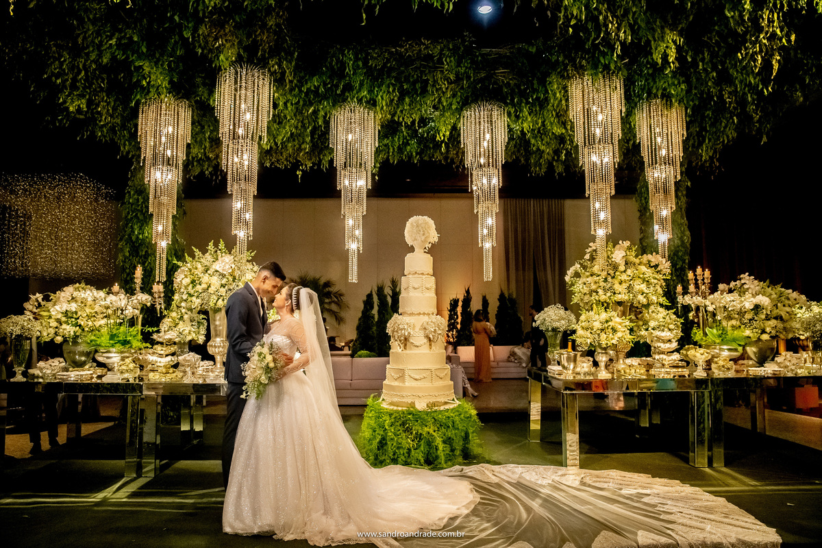 Com uma bela decoração, o casal posa a frente da mesa do bolo.