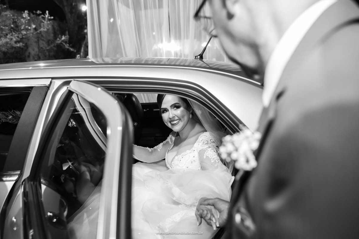 A noiva chegou, seu pai lhe da a mão para ela descer do carro.
