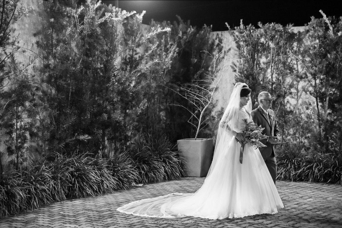 Já posicionada de braço dado com seu pai, ela aguarda o momento de sua entrada.