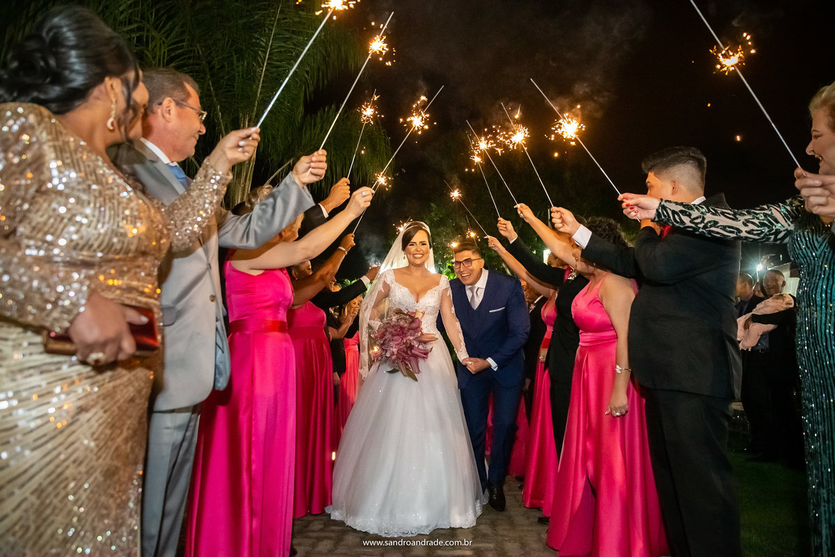 Passando corredor que os pais e padrinhos formaram no final da saída, com os sparkles de compondo esta belíssima fotografia.