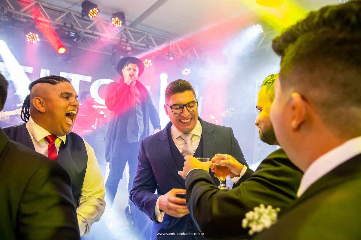Os amigos do noivo, se aproximando dele oferencendo uma taça de cerveja.