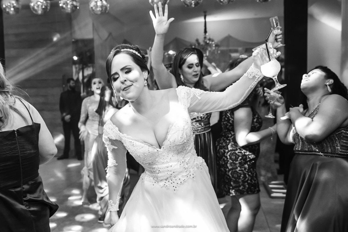A noiva dançando com a taça na mão.