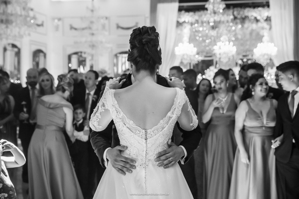 Os noivos dançando, uma fotografia preto e branca mostrando as costas da noiva e todos os detalhes do seu lindo vestido do ateliêr Maria Virginia.