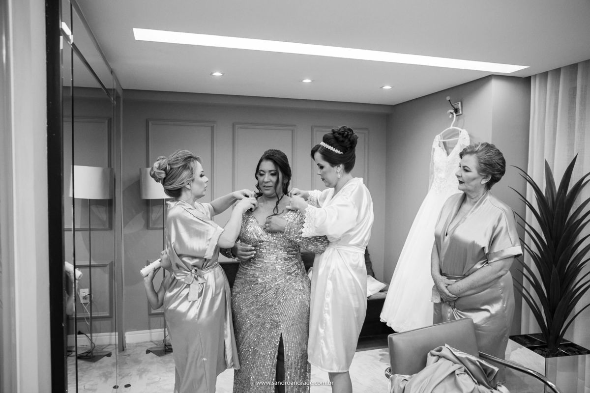 O click perfeito, ligado em todos os detalhes Sandro Andrade não dorme no ponto, enquanto a noiva ajuda sua sogra colocar o vestido junto com sua irmã, a mãe dela observa. Sandro Andrade é fotografo de casamentos em Brasília, fotografo premiado.