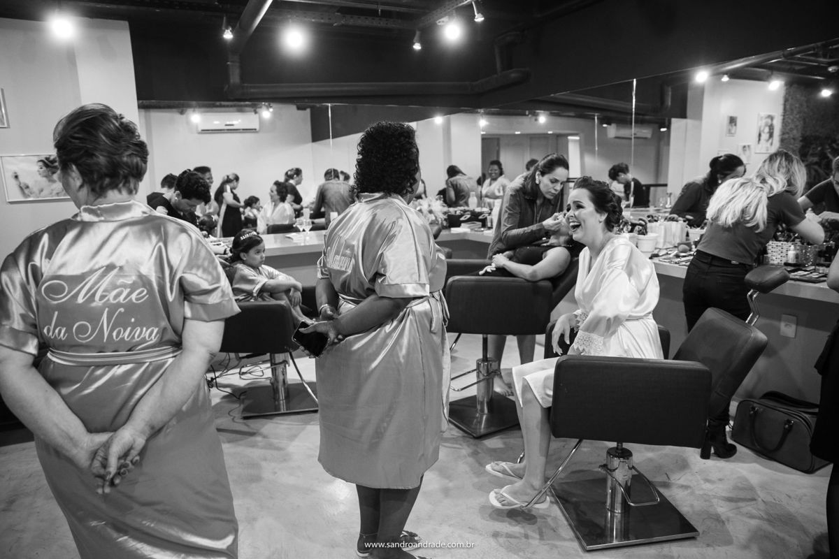 Uma gargalhada da noiva entre a mãe dela e suas madrinhas, fotografia PB.