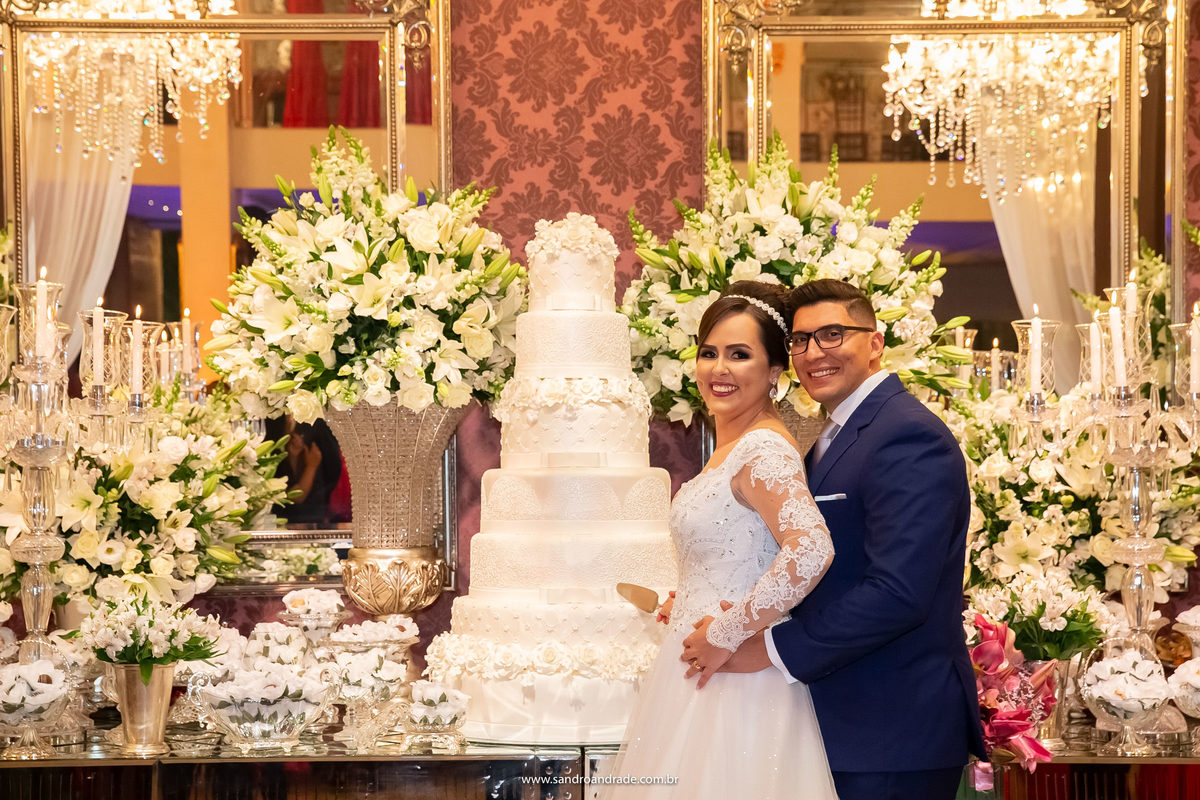 O corte do bolo, posicionados na mesa do bolo, eles olham para seu fotografo, um momento tradicional que não pode deixar de ter em todos os álbuns.