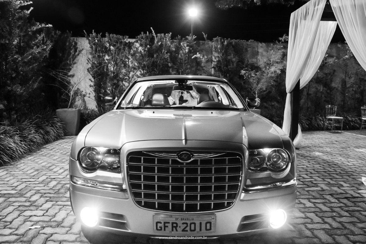 Em um belíssimo bentley eles se olham apaixonados, uma fotografia preto e branco.