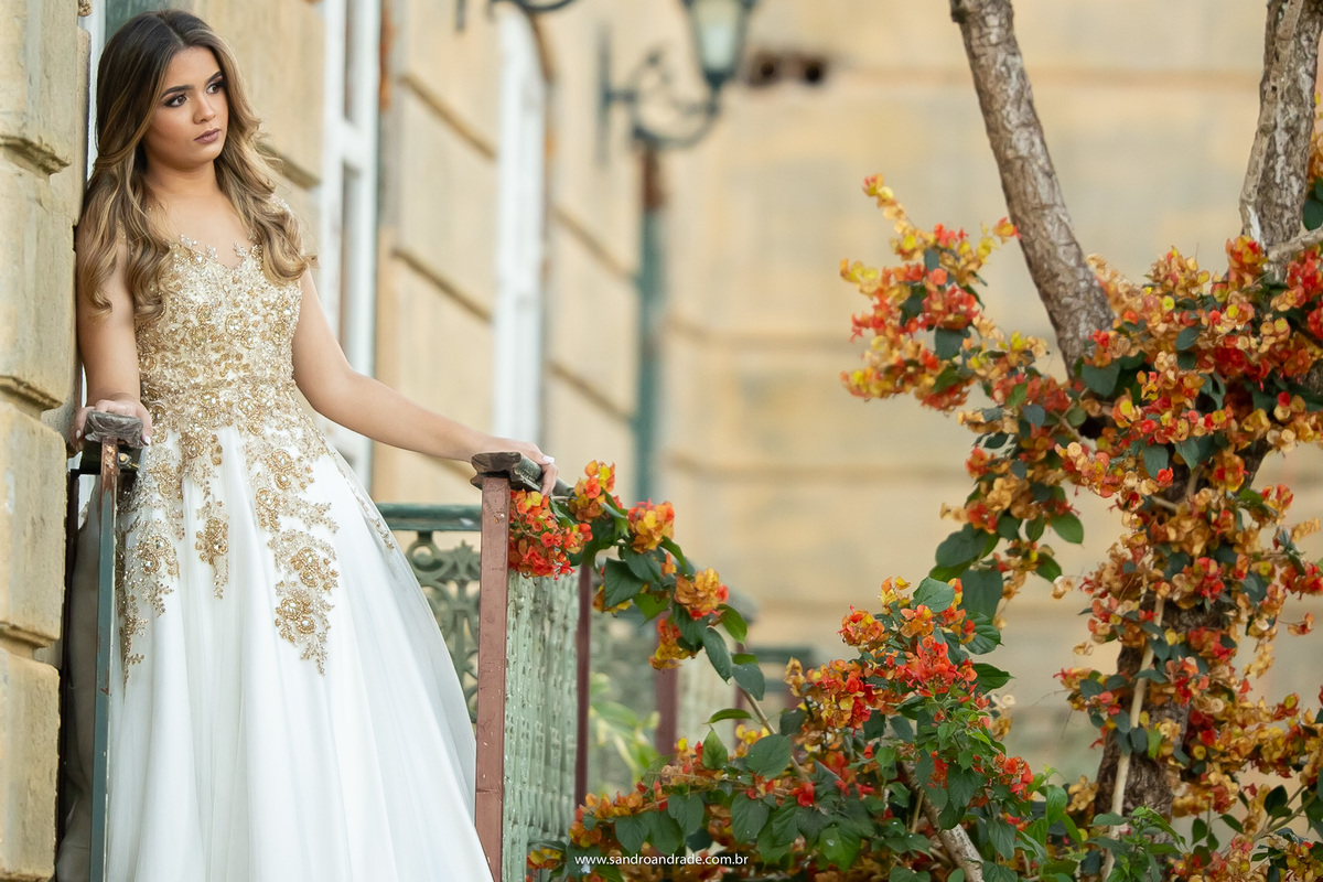 Nos fundos do pallazo, ela está encostada na parede, olhando para as flores de bougainvillea.