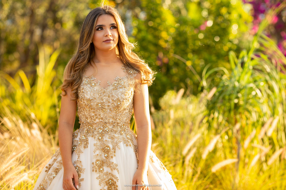Olhando para o céu, com um sorriso delicado e a luz do sol em contorno.