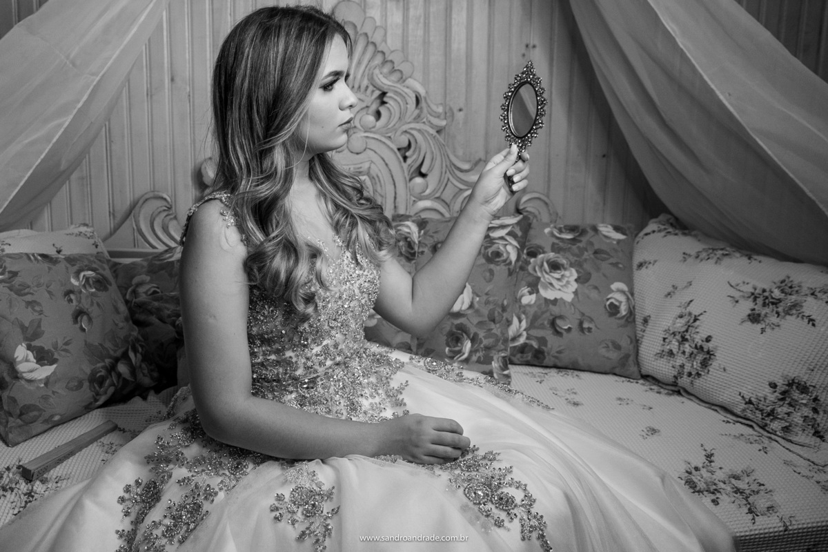 Ainda sentada e agora com um espelhinho de princesa na mão, ela se olha.