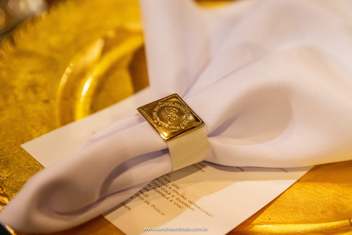 O guardanapo com as iniciais do casal, detalhes em dourado como o vestido da noiva.