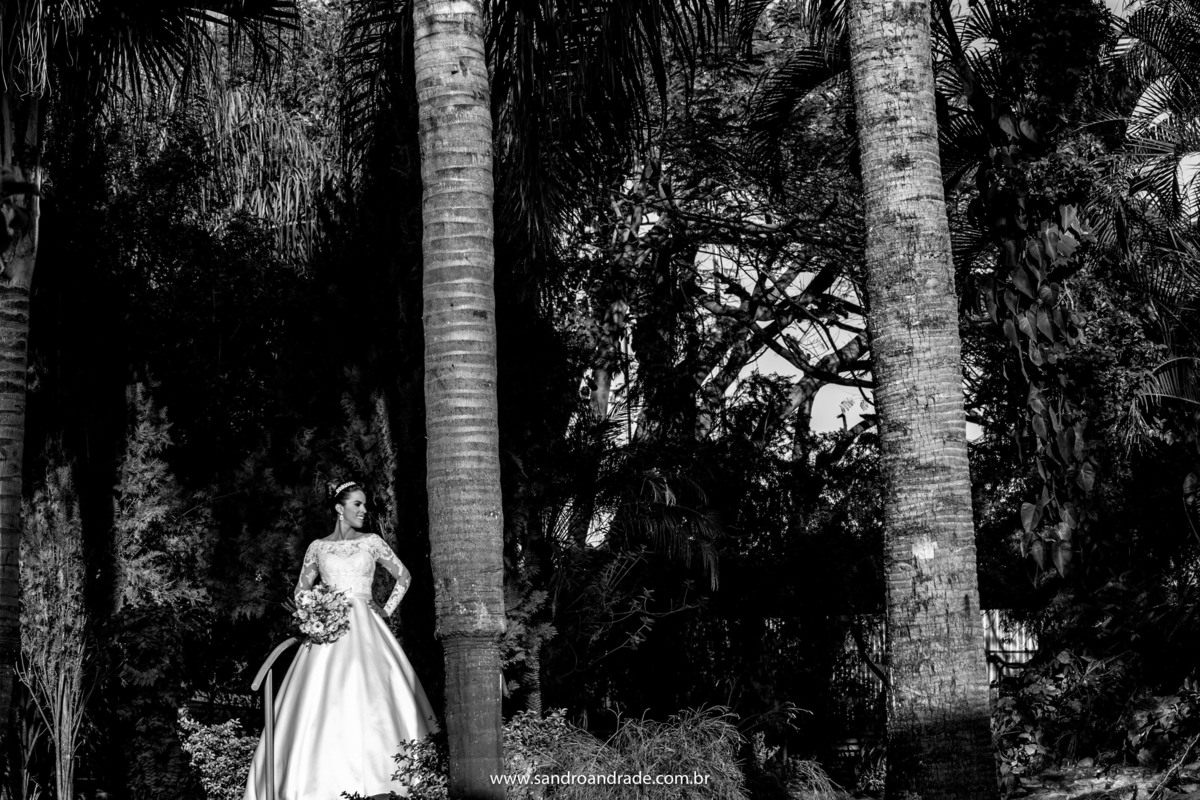 Na frente das árvores, em preto e branco, Taísa olha na direção lateral.