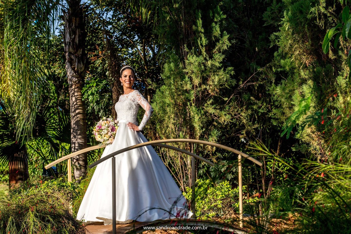 Numa ponte no meio do jardim do Porto Vitória, Taísa sorri para seu fotógrafo, fotografia colorida com um olhar único do nosso artista.