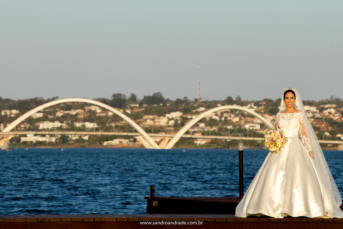 Agora no píer do Porto Vitória, com a majestosa ponte JK e o lago de  fundo, Taísa sorri e olha para as lentes de Sandro, de véu e com seu buque de noiva na mão.