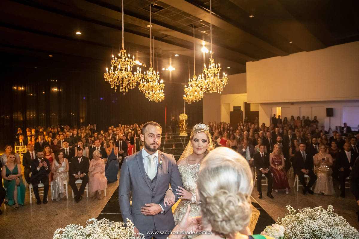 Uma fotografia de todo o espaço da cerimonia um pouco de cima, aparecendo os noivos e os convidados ao fundo.