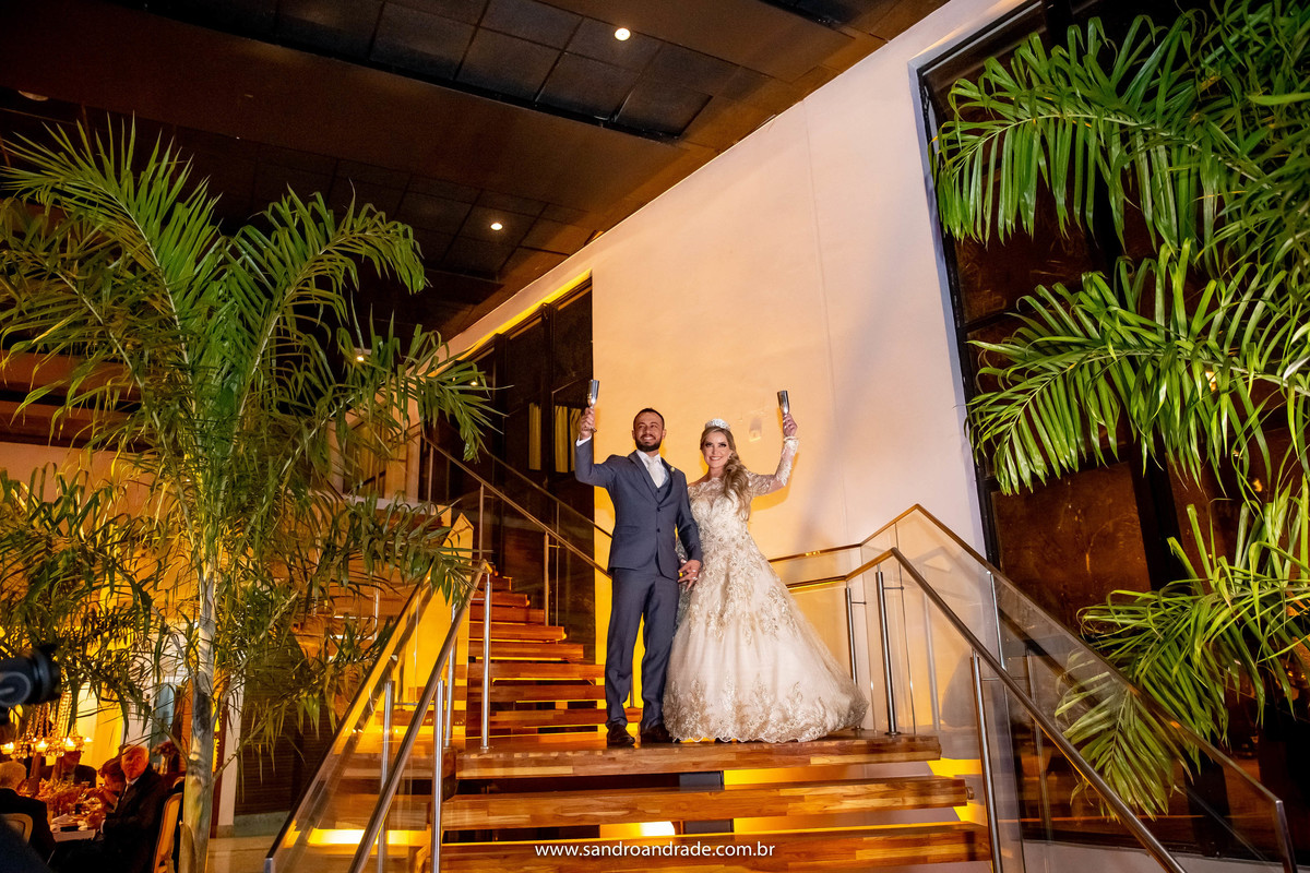 E juntos de mãos dadas eles erguem as taças em um brinde coletivo com seus parentes e amigos. E viva os noivos!