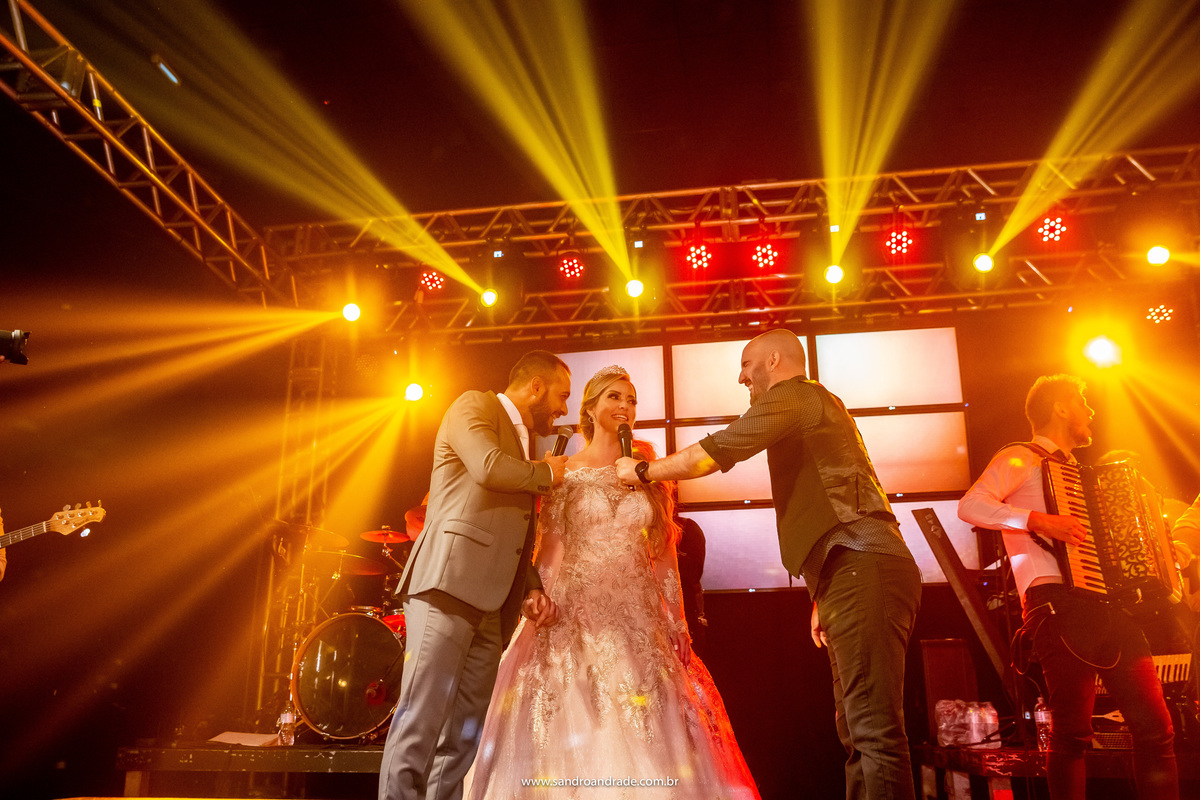 Cassia e Rafael cantando juntos, com o apoio do vocalista.