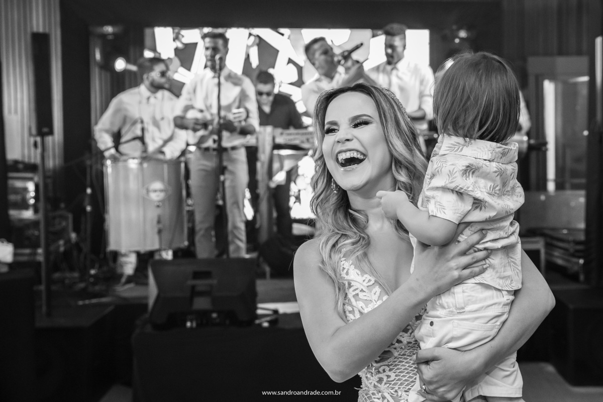 A noiva está feliz com o filho de um casal de amigos no colo.